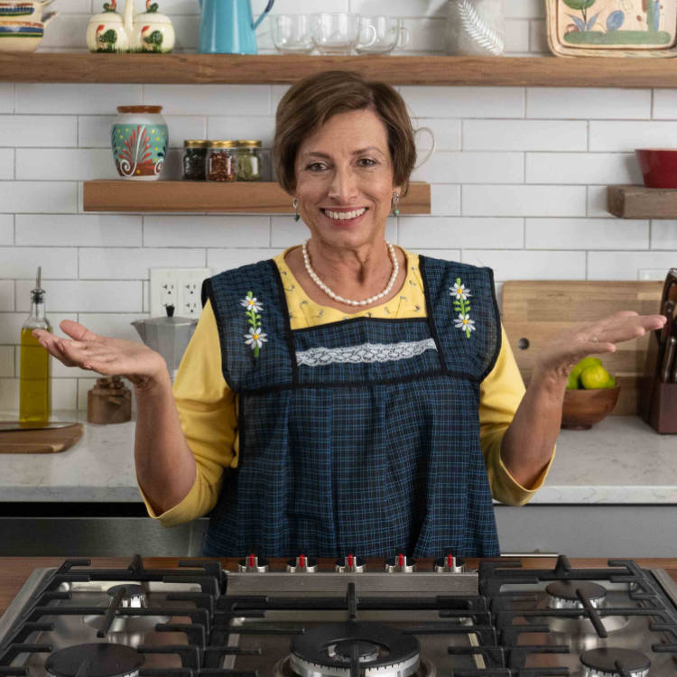 Abuela (representada por una actriz) en una cocina vistiendo un delantal